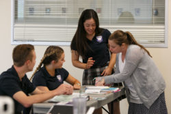 An instructor teaches three students at a desk