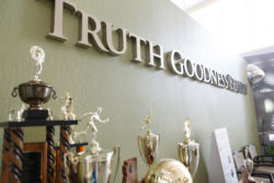 Trophies lining a wall that says Truth, Goodness, and Beauty