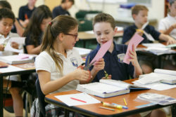 Students clip pink paper with scissors