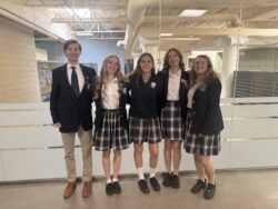5 students standing in front of glass wall